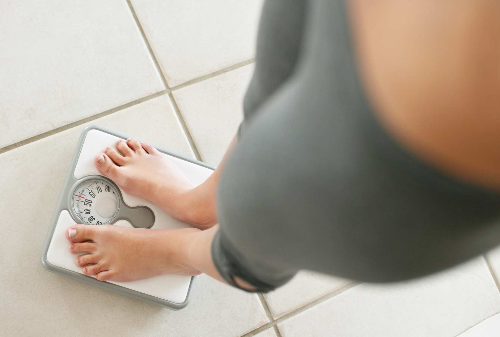 Low section of a dieting woman weighing herself